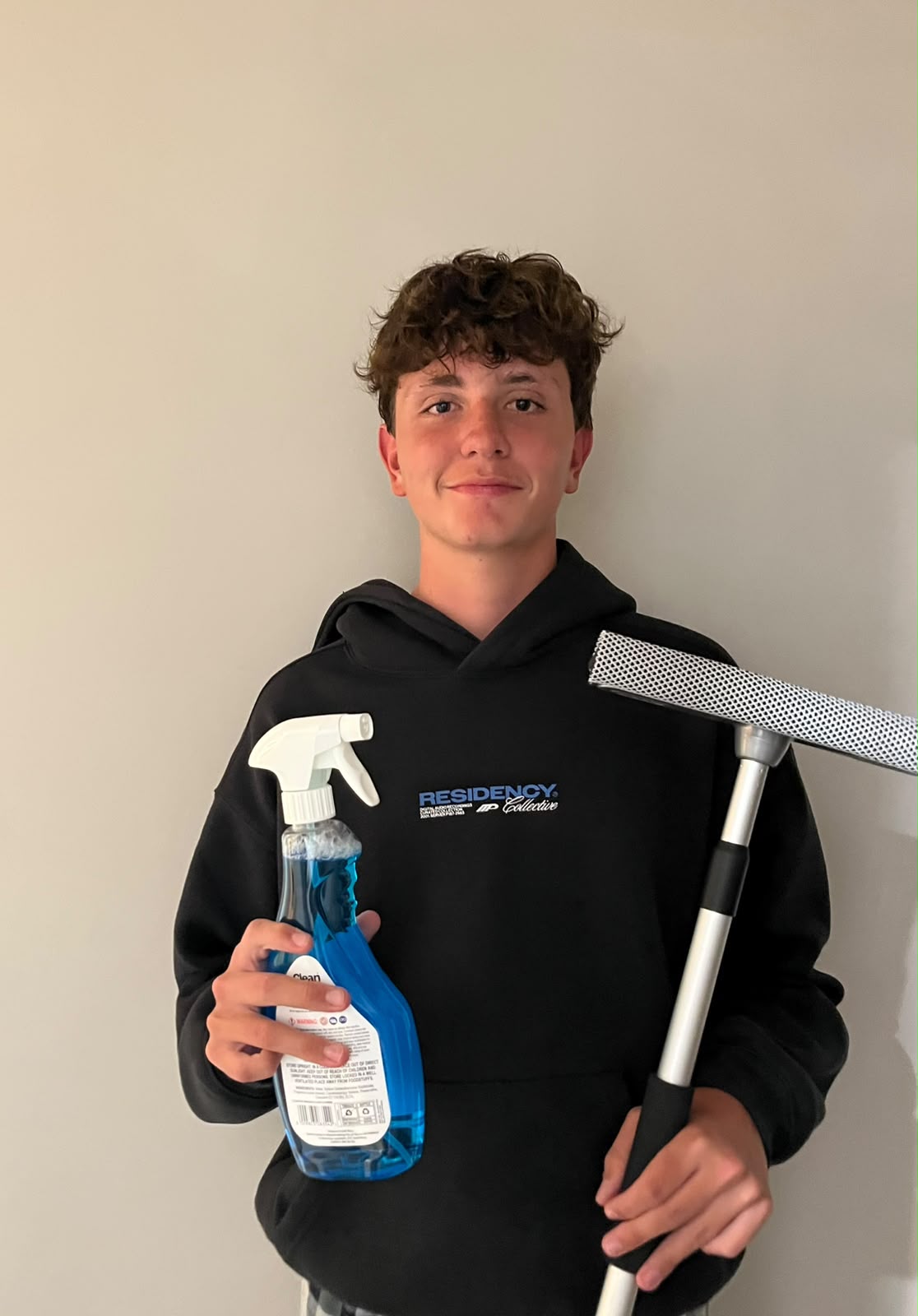 The Window Boys founder holding a spray bottle and a squeegee pole